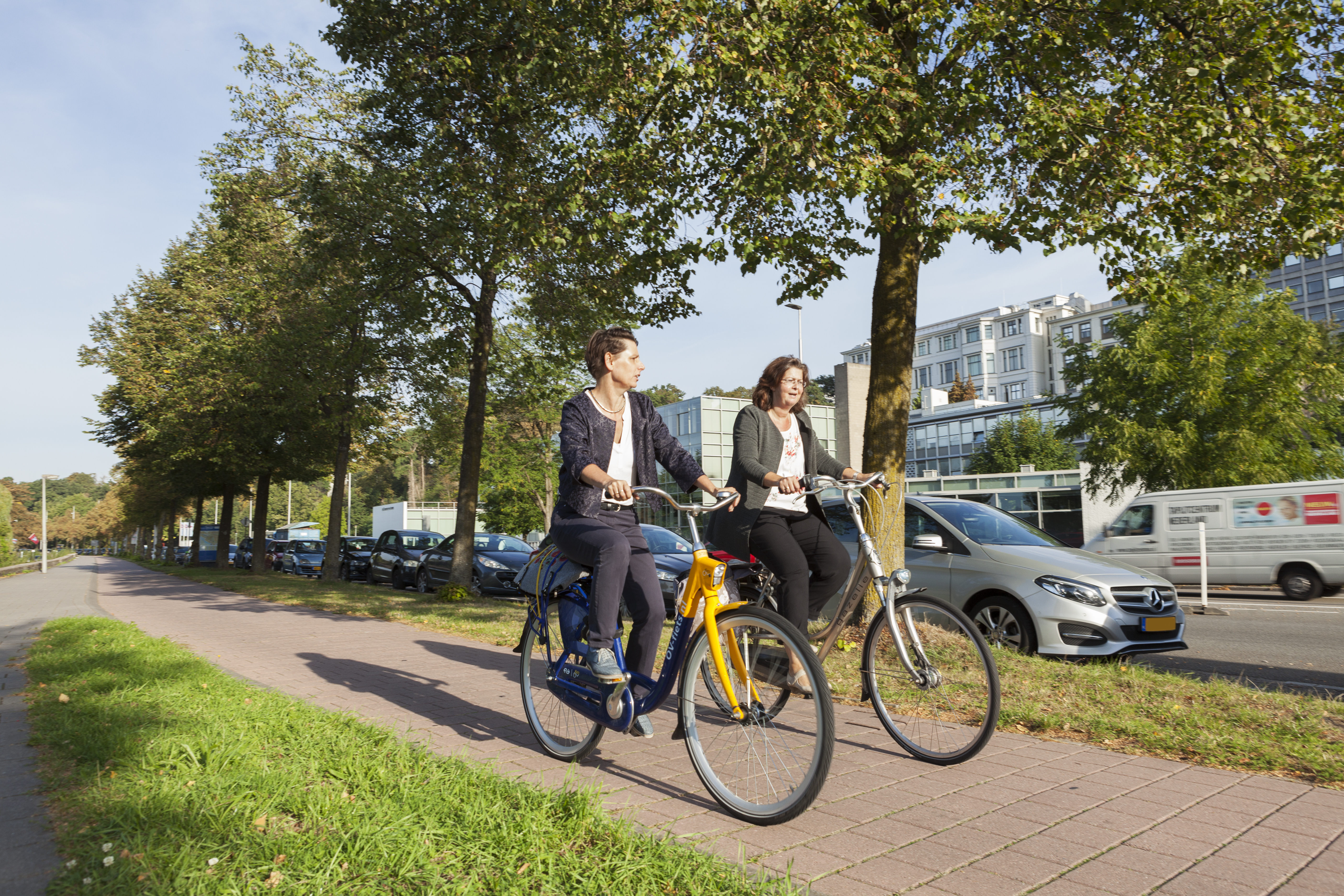 Twee fietsers in Arnhem, op eenOV-fiets en een gewone fiets